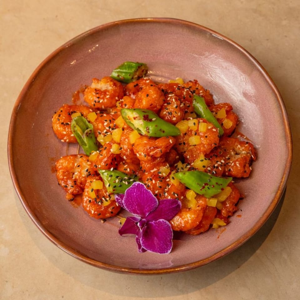 AquaSan's sweet and sour shrimp with pineapple, green peppers, sesame seeds, and an orchid.