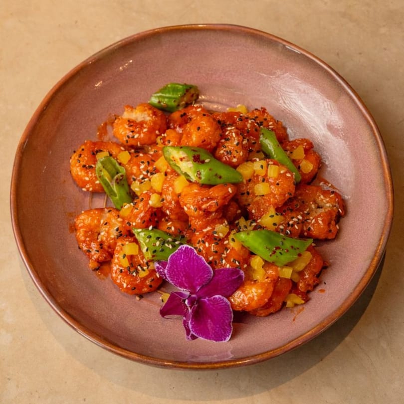 AquaSan's sweet and sour shrimp with pineapple, green peppers, sesame seeds, and an orchid.